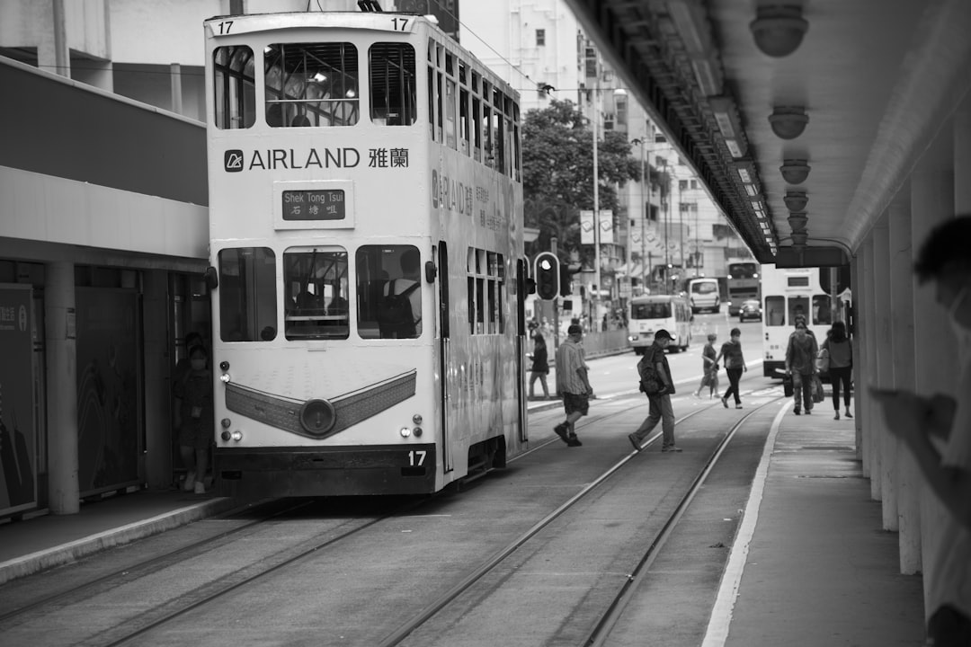 grayscale photo of people walking on sidewalk near tram