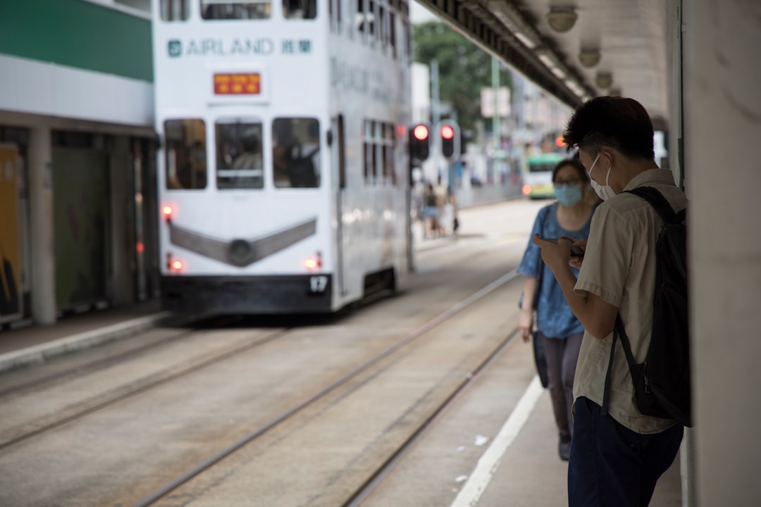 woman in brown coat standing beside white and yellow train during daytime