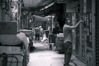 man in black t-shirt and pants standing near garbage containers