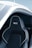 A sleek and modern car seat with black leather upholstery, featuring white stitching and a bold logo on the headrest. The seat is positioned within a partially open car door, revealing a stylish and futuristic design.