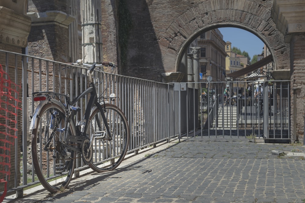 Bici da città blu parcheggiata accanto a una recinzione metallica grigia durante il giorno
