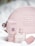 Soft pink leather pouch embossed with a geometric pattern, surrounded by luxury cosmetic items including a tube, a bottle of perfume, and a lipstick. The setup conveys a sense of elegance and sophistication.