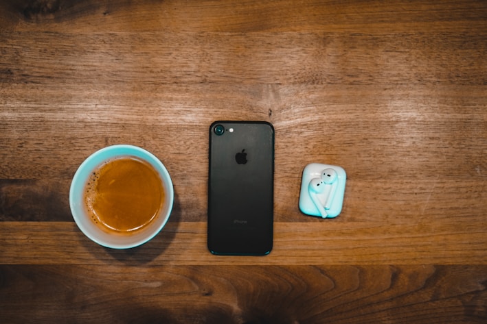A sleek black phone case resting on a wooden table beside a cup of coffee