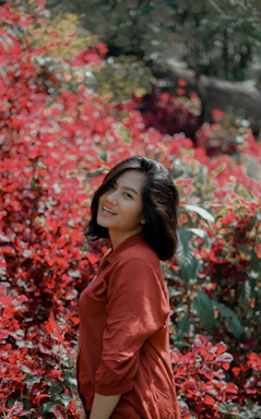 A warm portrait of Angie smiling in her lush garden surrounded by healthy plants.