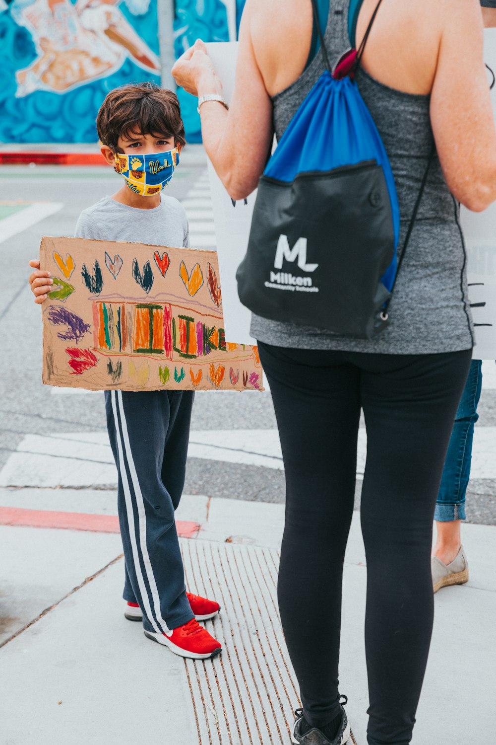 woman in blue tank top and black leggings holding brown and green cardboard box