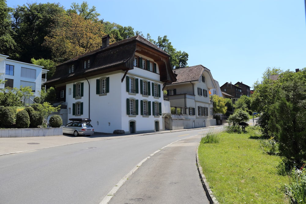 Maison en béton blanc et brun à côté d’arbres verts pendant la journée