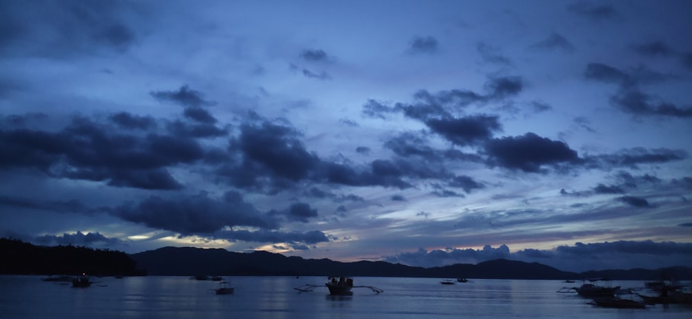 silhouette of people riding boat on sea under cloudy sky during daytime