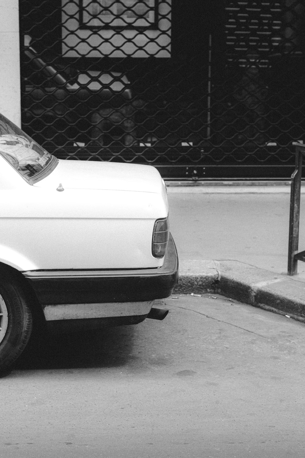 white car parked beside gray metal fence