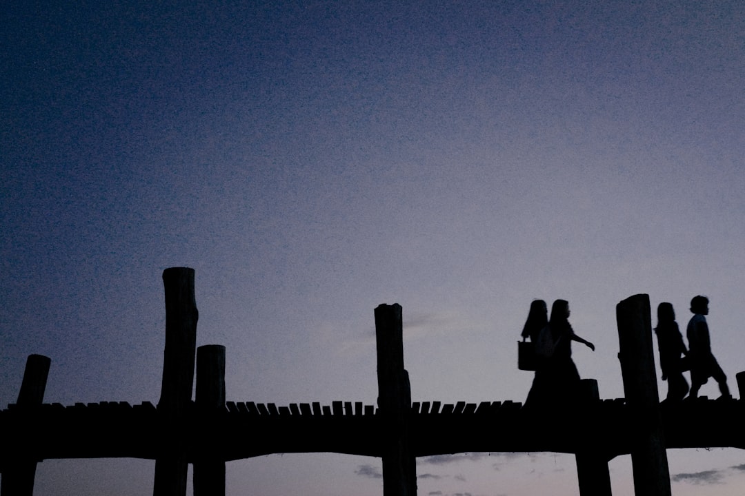 silhouette of man standing on wooden fence during daytime