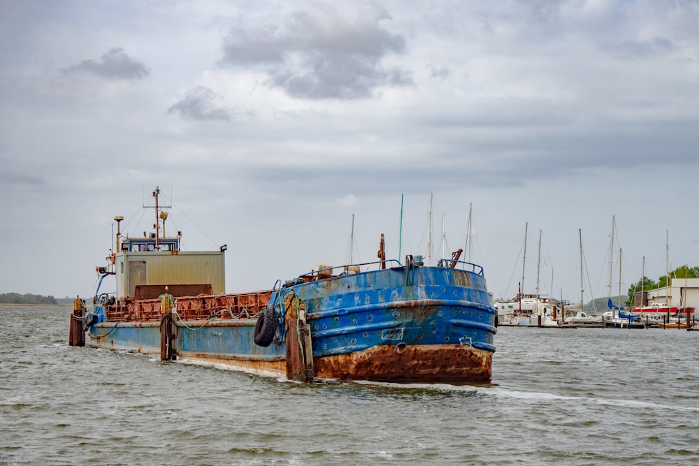 blue and brown ship on sea under white clouds during daytime