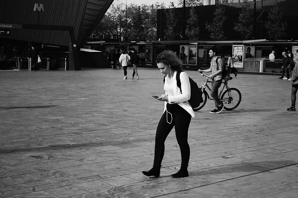 woman in white long sleeve shirt and black pants riding bicycle on gray concrete pavement