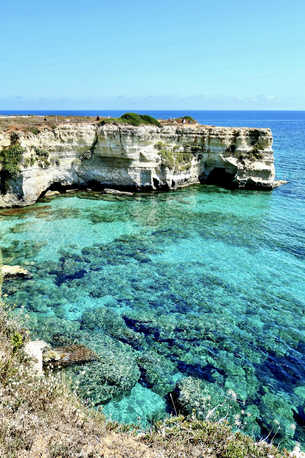 formação rochosa marrom no mar azul durante o dia