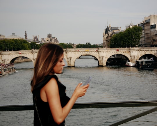 woman in black tank top standing near body of water during daytime in Pont des Arts France