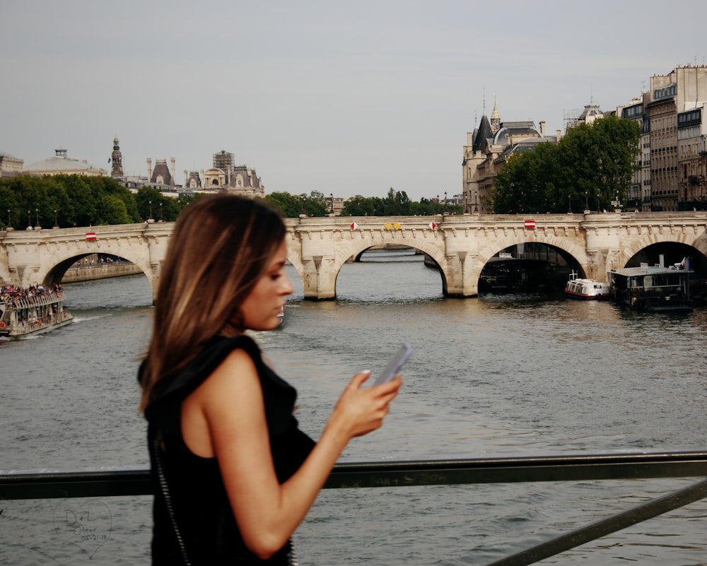 woman in black tank top standing near body of water during daytime