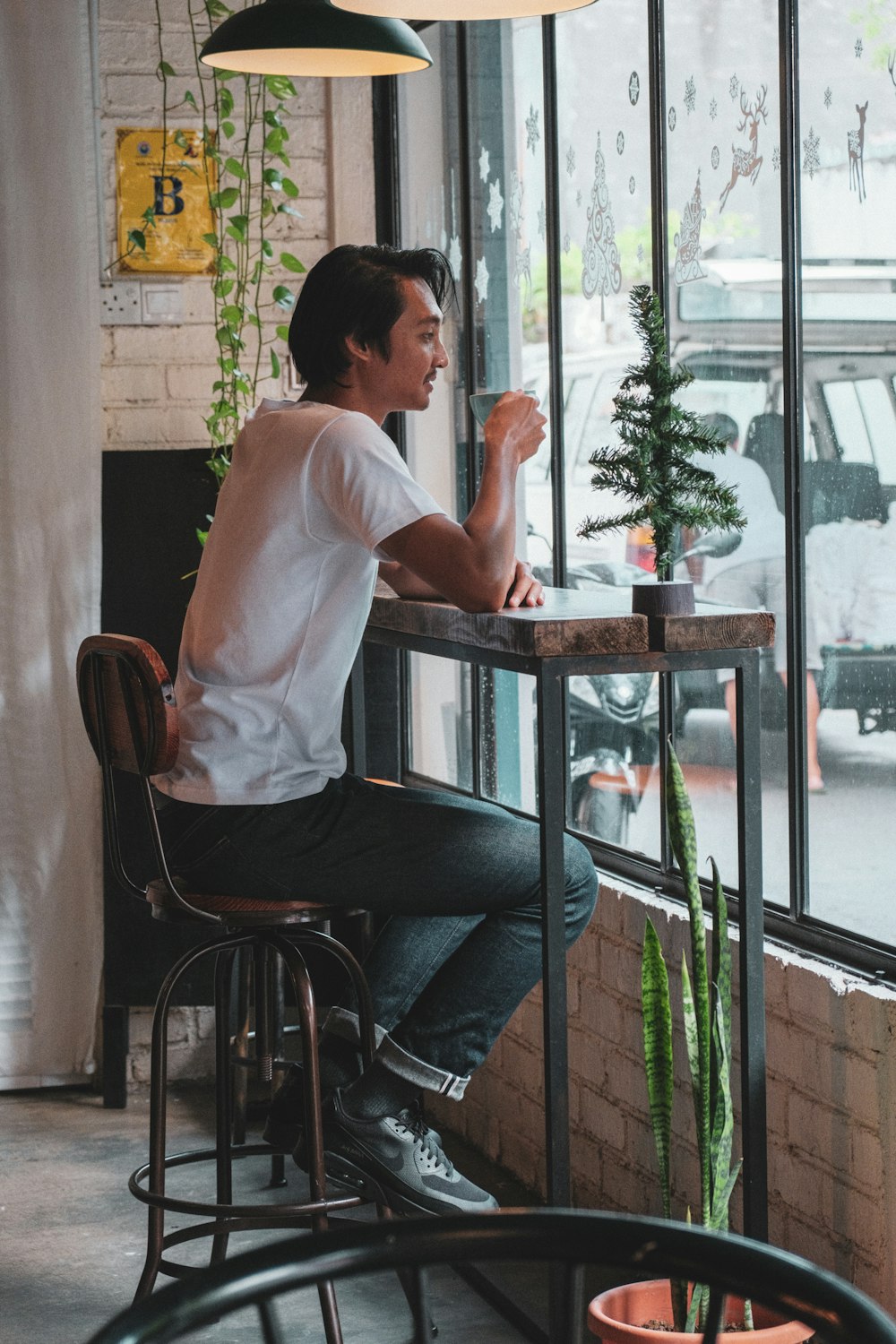 man in white dress shirt and blue denim jeans sitting on brown wooden chair