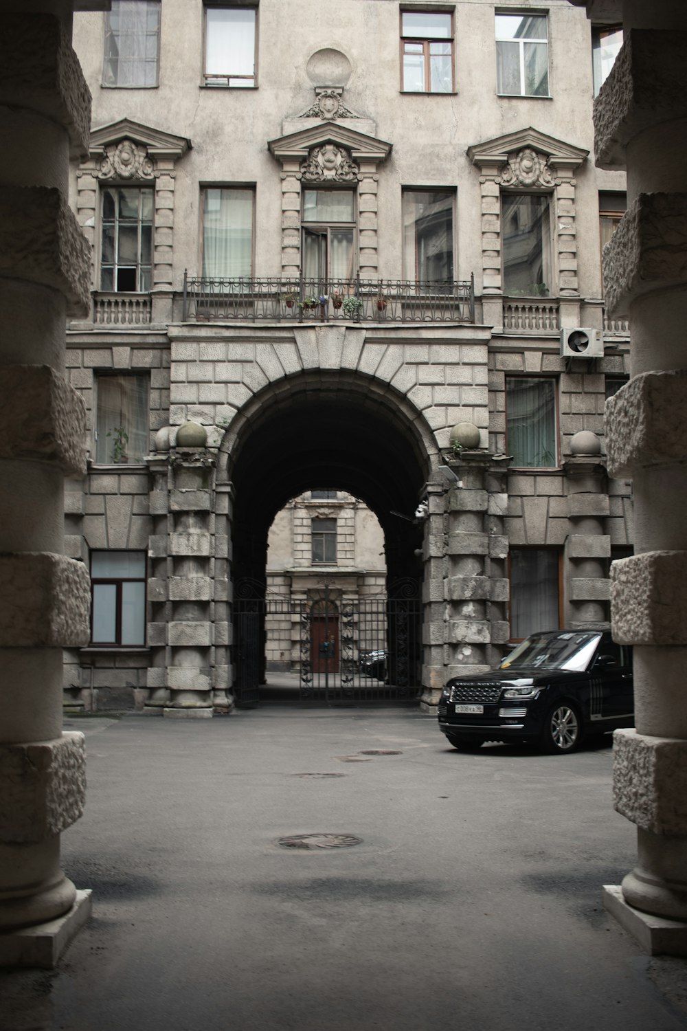 black car parked beside beige concrete building during daytime