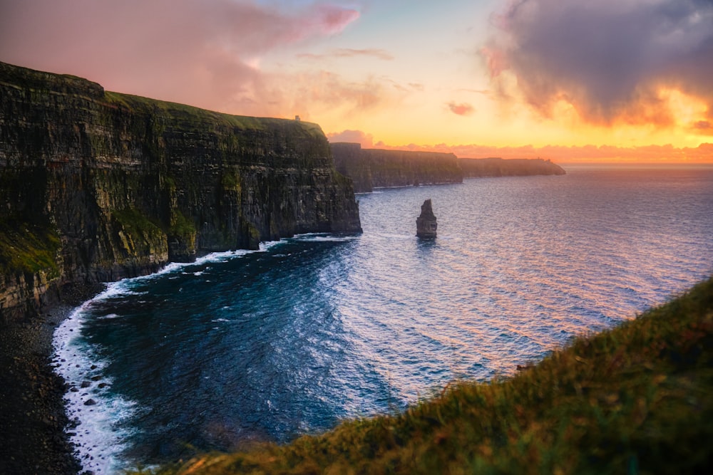 green and brown mountain beside body of water during sunset