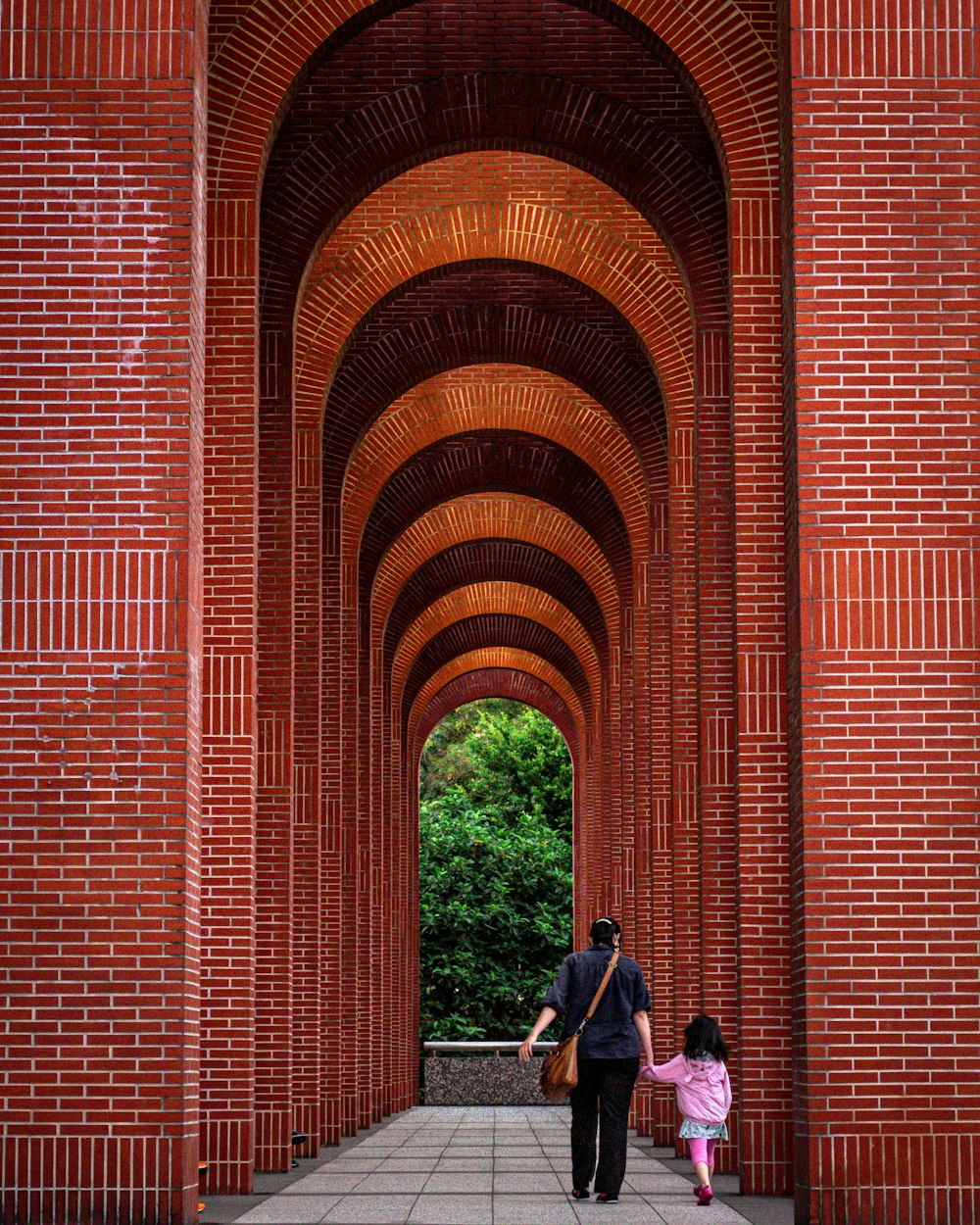 man and woman standing beside red brick wall during daytime
