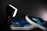 Close-up of a stylish pair of deep blue Makano Shoes glowing softly against a black background.