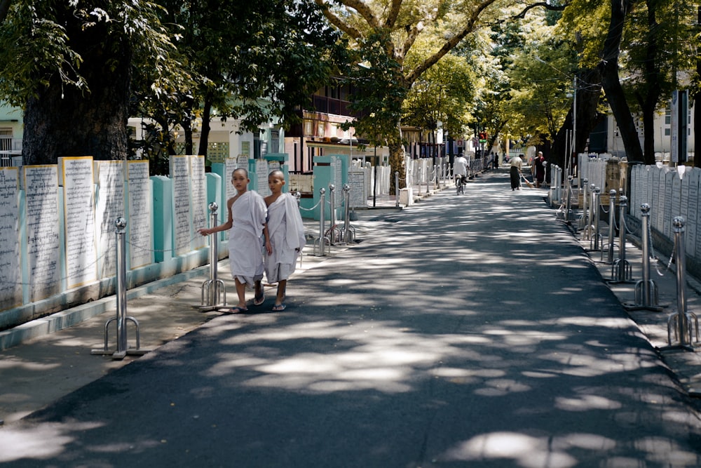 2 men in white dress shirt walking on sidewalk during daytime