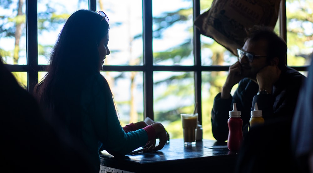 woman in blue long sleeve shirt sitting beside window during daytime