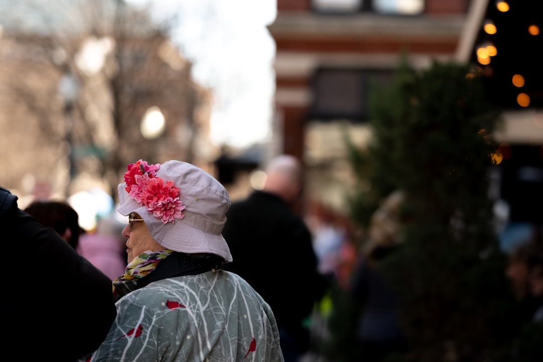 person in gray and red floral shirt with white and pink flower on head