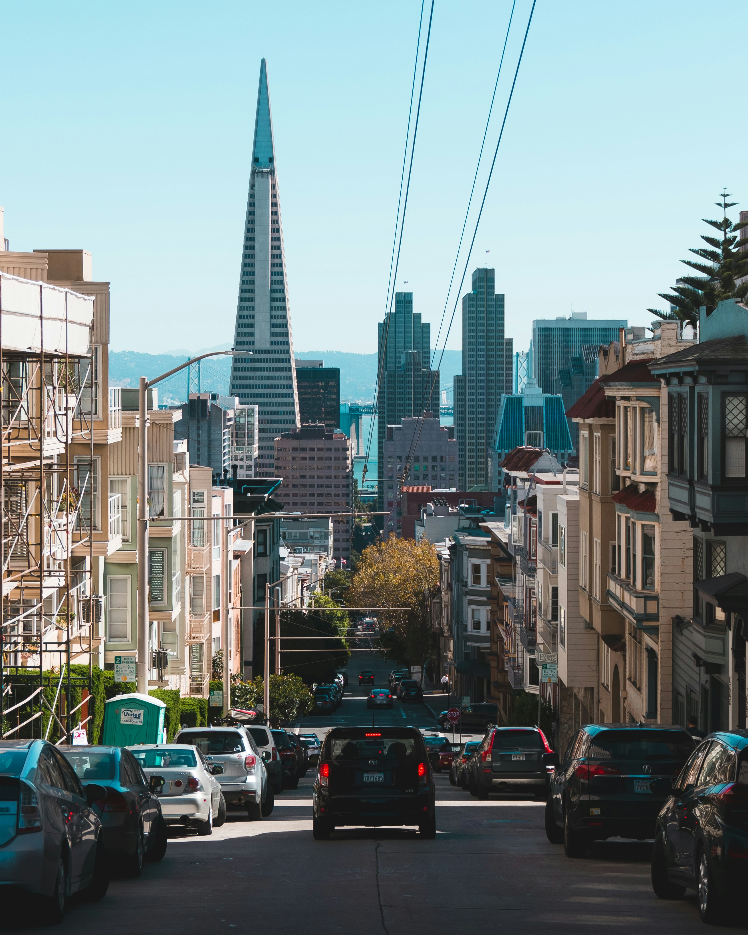 High street-level view of San Francisco’s Financial District with the Transamerica Pyramid rising prominently in the background, surrounded by modern office buildings and urban energy.