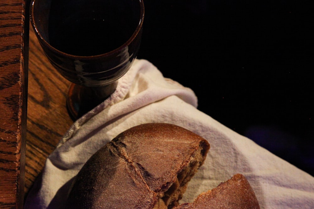 透明なコップの横の白い布地にパン