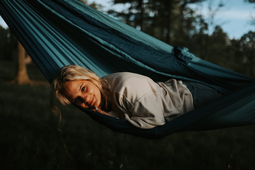 woman in gray jacket and black pants sitting on blue hammock