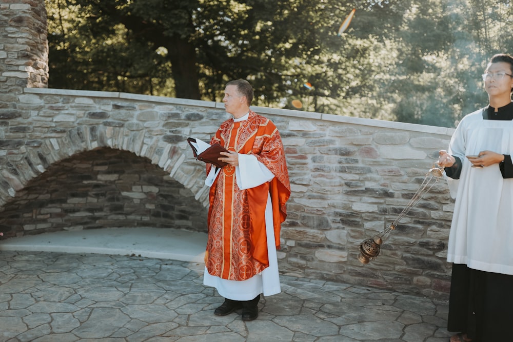 man in red and white robe standing on gray concrete floor during daytime