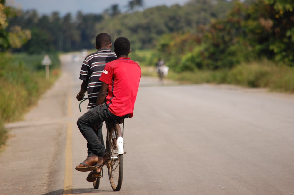 man in red shirt and black pants riding bicycle during daytime