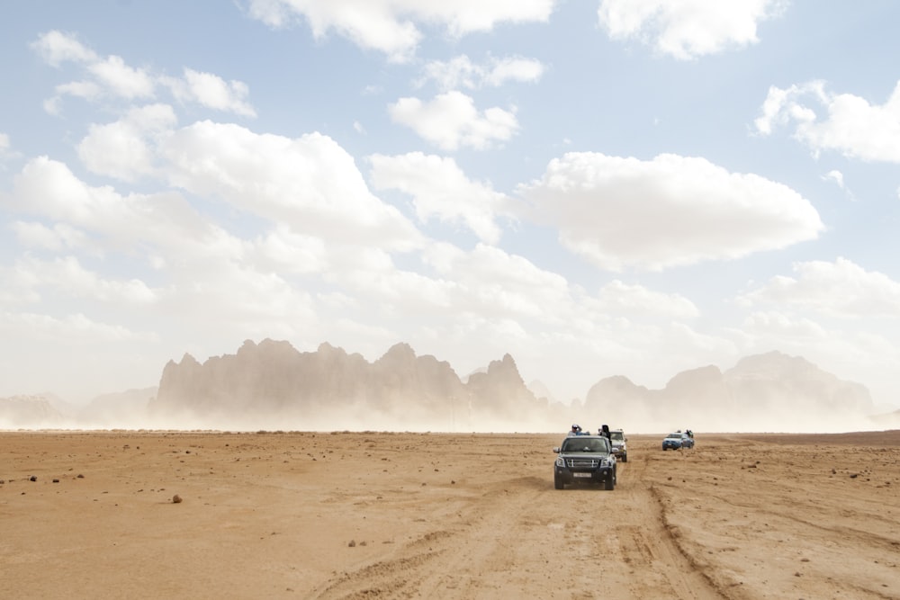 black suv on brown sand under white clouds during daytime