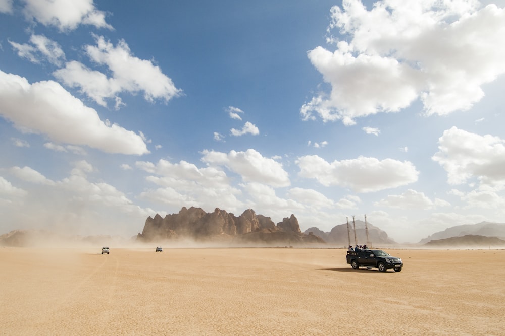 Auto nera su sabbia marrone sotto cielo blu durante il giorno