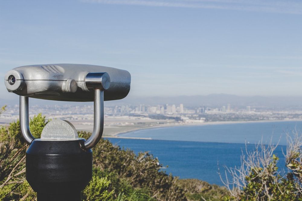 black coin operated binoculars on brown and green grass field near body of water during daytime