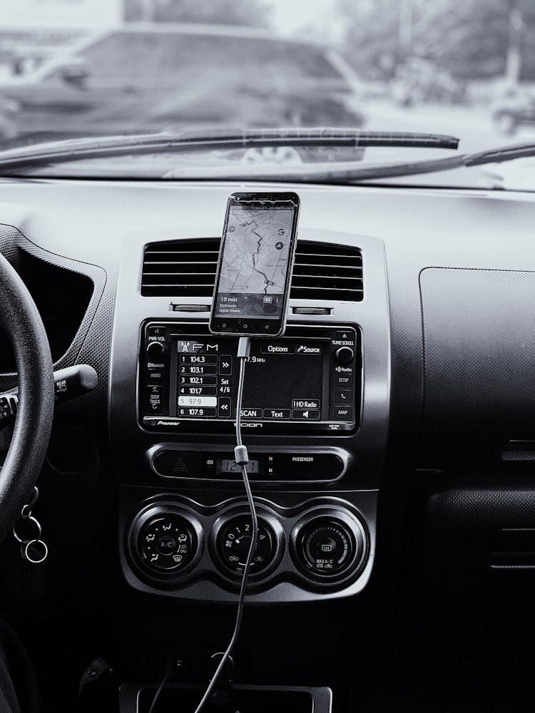 An iPhone with a cable, sitting in front of a modest dashboard.