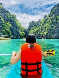 woman in orange and black life vest sitting on yellow boat on blue sea during daytime