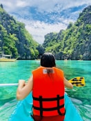 woman in orange and black life vest sitting on yellow boat on blue sea during daytime