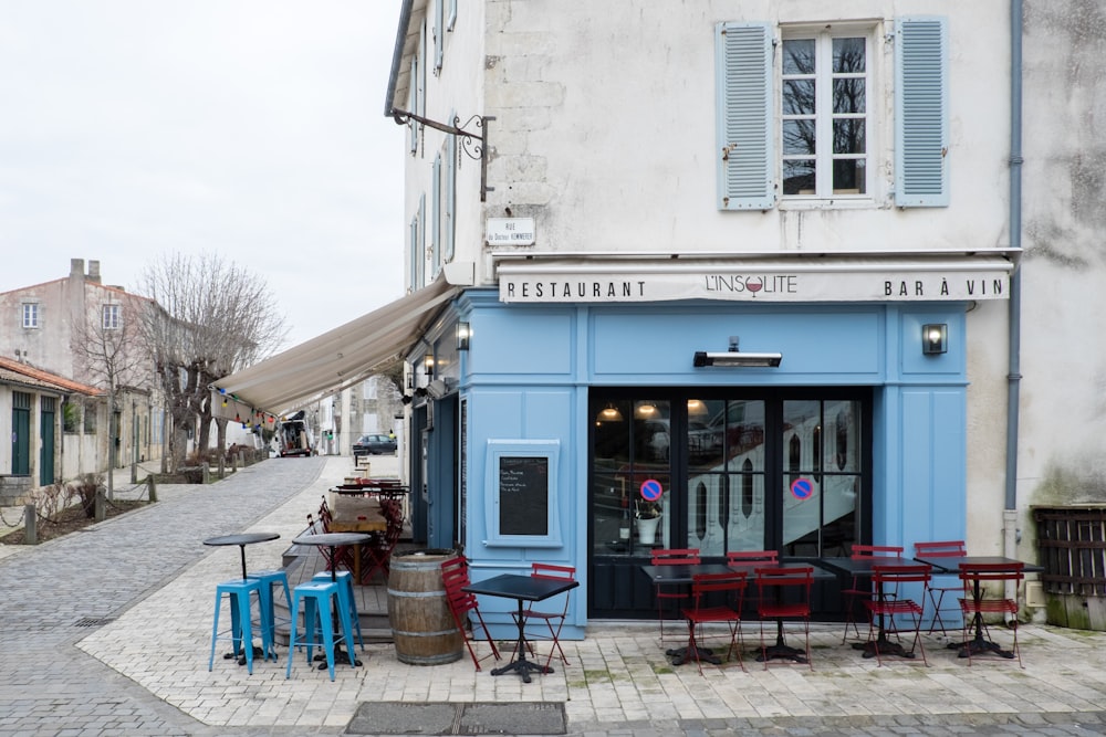 white concrete building with blue plastic chairs and tables