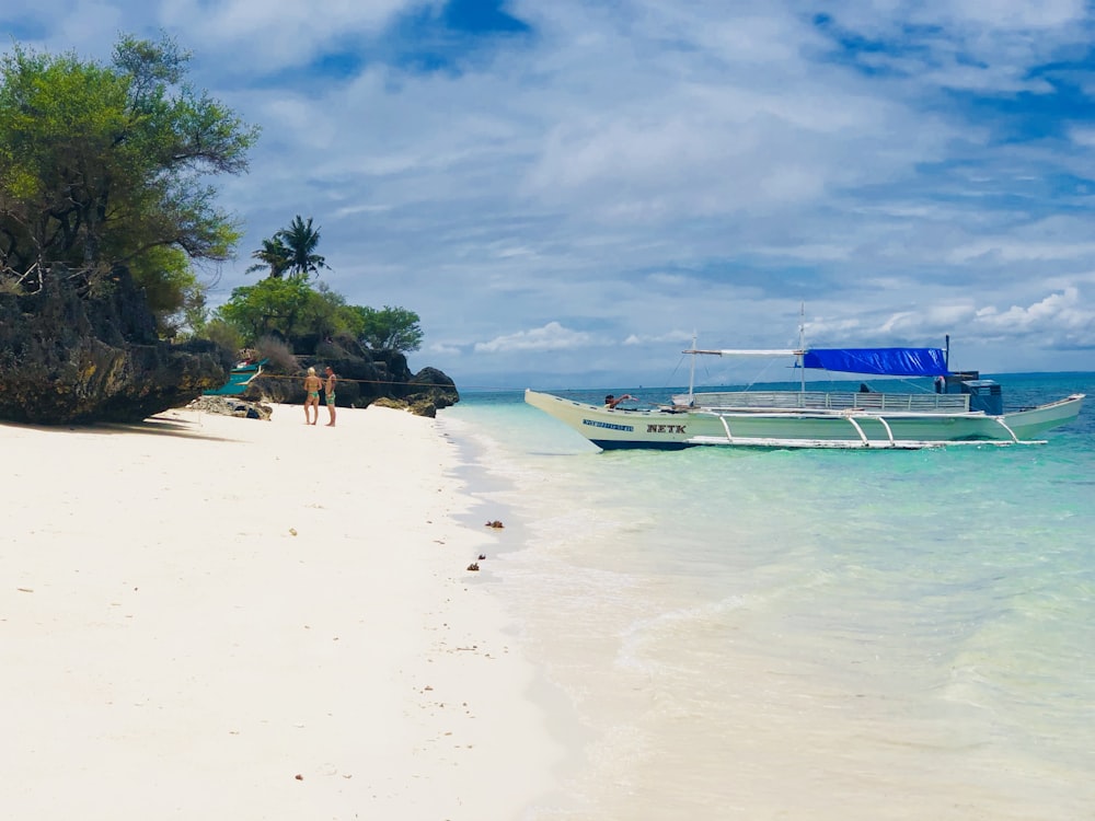 white and blue boat on white sand beach during daytime