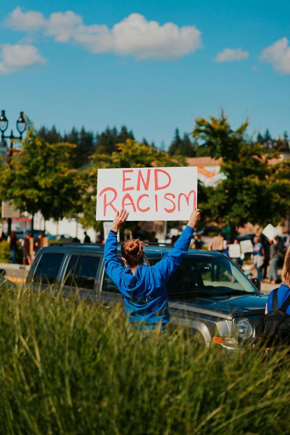 woman in blue jacket holding white and black happy birthday signage