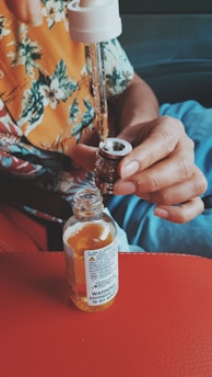 person holding white labeled glass bottle
