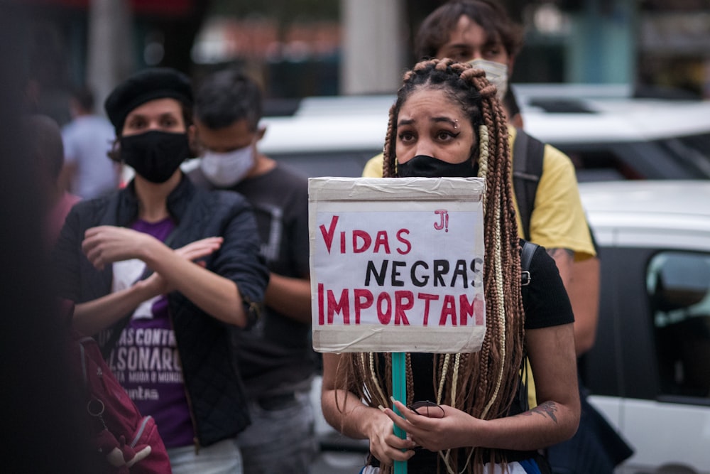 a woman with dreadlocks holding a sign