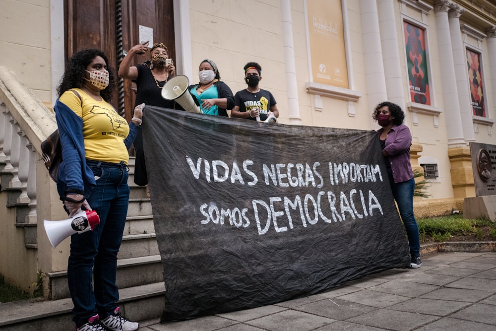 a group of people holding a sign on a sidewalk