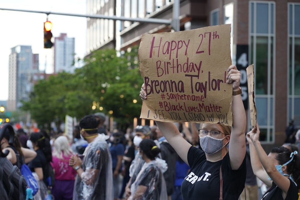 people holding brown wooden signage during daytime