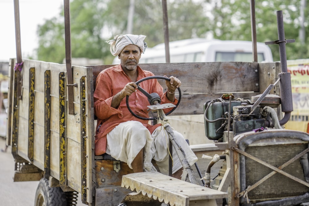 man in brown jacket sitting on yellow tractor