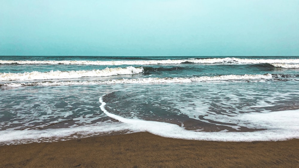 sea waves crashing on shore during daytime