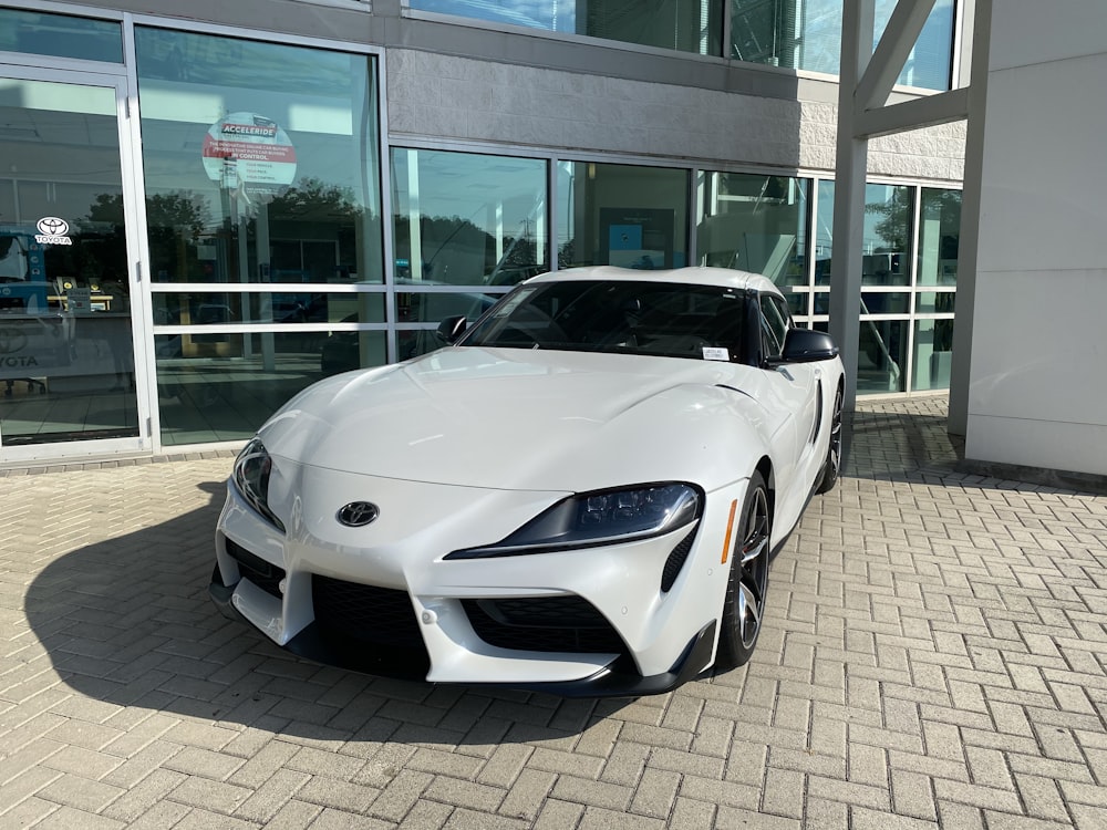 white porsche 911 parked near glass building