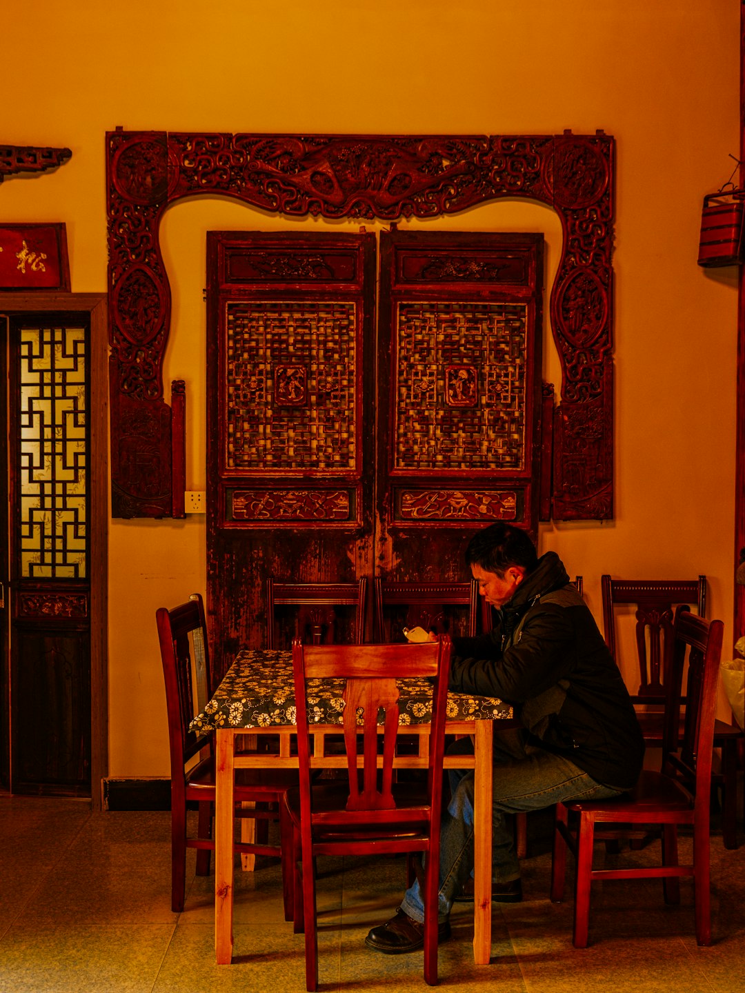 man in black jacket sitting on brown wooden chair