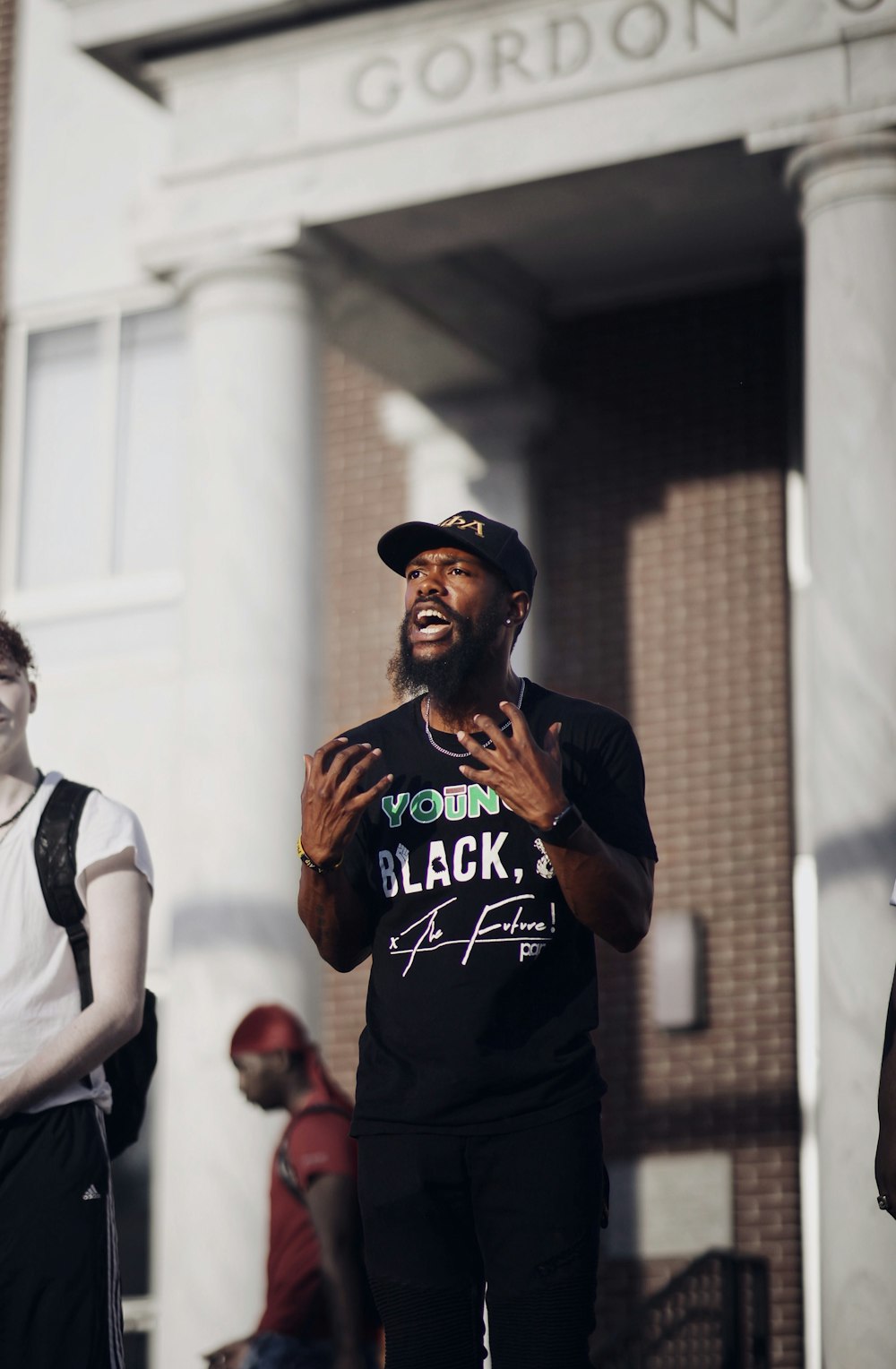 man in black and orange crew neck t-shirt standing beside man in white t-shirt