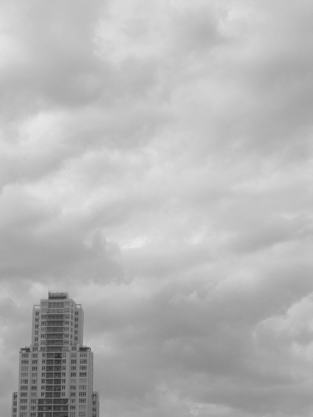 Graustufenfoto von Stadtgebäuden unter bewölktem Himmel